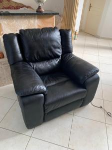 un sofá de cuero negro sentado en una sala de estar en Charmante maison au calme, en Sainte-Maure