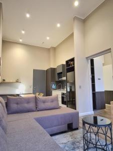 a living room with a purple couch and a kitchen at Top Floor Penthouse - Overlooking Times Square Casino in Pretoria