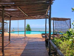 a wooden walkway leading to a swimming pool with a view of the ocean at Saadani Safari Lodge in Saadani