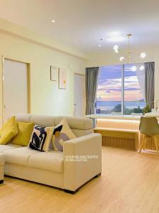 a living room with a couch and a large window at QUEENSLAND SUITES at Aru Suites, Kota Kinabalu in Kota Kinabalu