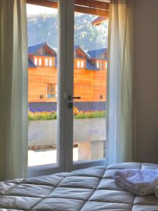 een slaapkamer met een bed en een groot raam bij Hotel Crismalu in San Martín de los Andes
