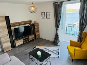 ein Wohnzimmer mit einem TV, einem Sofa und einem Tisch in der Unterkunft Vila Mila Volosko Opatija in Opatija