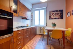 a kitchen with wooden cabinets and a table with yellow chairs at Casa Martina- Airport free shuttle-H24 in Bergamo