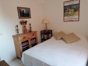um quarto com uma cama branca e uma cómoda em madeira em 4SAP22 Appartement climatisé avec double terrasses em Collioure
