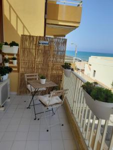 eine Terrasse mit einem Tisch und Stühlen auf dem Balkon in der Unterkunft Riviera la lanterna in Scoglitti