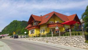 a yellow house with a red roof on the side of a road at Apartments and Rooms With View on Bled in Bled