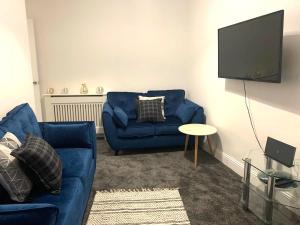 Glasgow, Bothwell, 3 bed, Suitable for Long Stays في Bothwell: غرفة معيشة مع أريكة زرقاء وتلفزيون