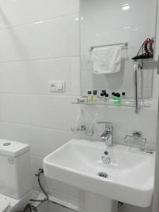 La salle de bains blanche est pourvue d'un lavabo et de toilettes. dans l'établissement Queens 2 hotel, à Tachkent