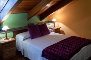 een slaapkamer met een groot bed met paarse kussens bij Apartamentos Rurales Las Mestas in Puenteciella