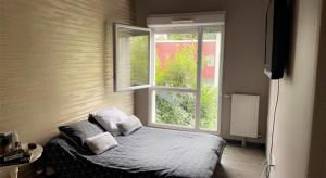 Schlafzimmer mit einem Bett und einem Fenster in der Unterkunft Chambre et salle de bain privée dans maison proche Paris et Disney in Valenton