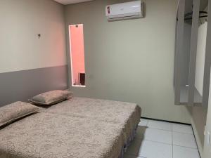 a small bedroom with a bed with a window at Residencial Milagre 202 in Juazeiro do Norte