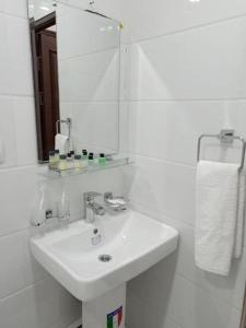 La salle de bains blanche est pourvue d'un lavabo et d'un miroir. dans l'établissement Queens 2 hotel, à Tachkent