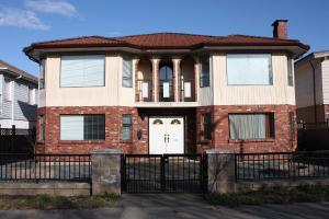 a brick house with a white door and a black fence at Neocolonial Nouveau Kensington in Vancouver