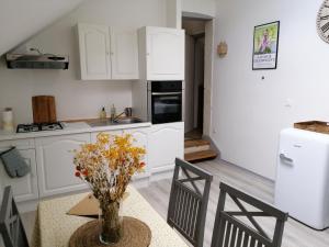 una cocina con armarios blancos y una mesa con un jarrón de flores en Bel appt 3 pièces, à l'étage, jardin privatif, au calme, 10 mn Saumur et CNPE en Varennes-sur-Loire