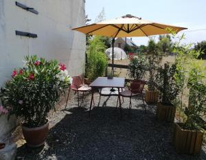 una mesa y sillas con sombrilla en un patio en Bel appt 3 pièces, à l'étage, jardin privatif, au calme, 10 mn Saumur et CNPE en Varennes-sur-Loire