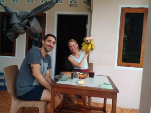 Un homme et une femme assis à une table avec une bande de bananes dans l'établissement Fajar Home Stay Batukaras, à Batukaras