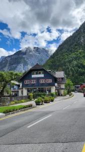 um edifício ao lado de uma estrada com uma montanha em Fenix Hall Boutique Hotel Hallstatt em Hallstatt