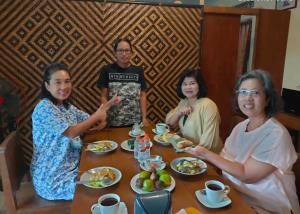 Eine Gruppe von Frauen, die an einem Tisch sitzen und Essen essen. in der Unterkunft Efata Homestay in Borobudur