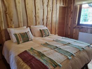 a bed in a room with a wooden wall at PARCELA DE AGRADO LAGO RANCO todas las instalaciones con uso exclusivo in Lago Ranco
