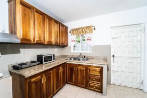 Una cocina con armarios de madera, fregadero y microondas. en Skyline Suites, breathtaking mountains & city view apts, en Montego Bay