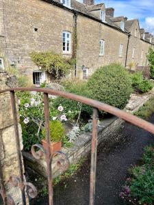 an old iron fence with flowers in front of buildings at Why Not in Stow on the Wold
