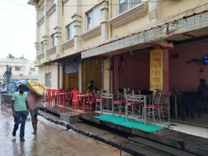 Un couple marchant dans une rue sous la pluie avec un parapluie dans l'établissement Divine view - 1 bhk AC - Swarna Bhavan, à Purî