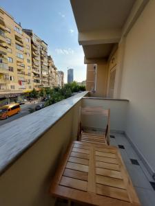 uma varanda com um banco de madeira num edifício em Vila TAFA Apartments em Tirana