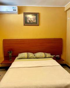 un letto con testiera in legno in una stanza di Hostal Montesa a Guayaquil
