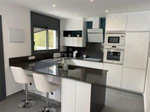 a kitchen with white cabinets and white appliances at Lux@Spa in Vallirana