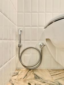 a white tiled bathroom with a hose on a toilet at Chambre d’hôtes - Marais in Paris