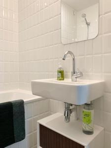 a white bathroom with a sink and a bath tub at Chambre d’hôtes - Marais in Paris