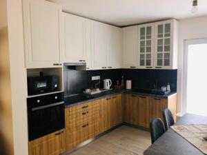 a kitchen with white cabinets and black appliances at ubytovanie u MITIho in Szalóc