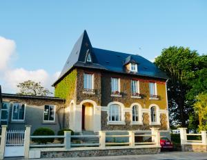 une grande maison avec un toit noir dans l'établissement Du marais à la mer, à Lessay