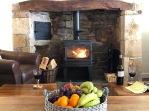 una cesta de fruta en una mesa frente a la chimenea en Church View - c. 1750 cosy character cob cottage., en Hatherleigh