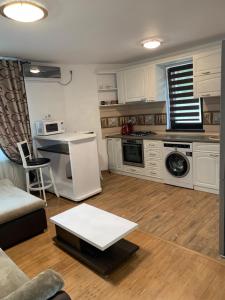 a kitchen with white cabinets and a table in a room at Apartament Micsunelelor in Iaşi