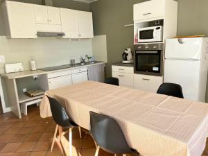 a kitchen with a table and a white refrigerator at Maison de campagne in Rions
