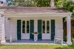 un porche con persianas verdes y 2 sillas en Steele Cottage en Vicksburg