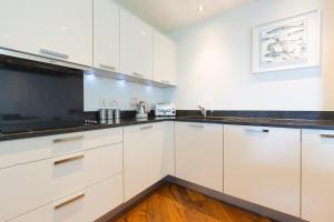 a kitchen with white cabinets and black counter tops at Coast in St Ives