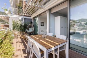 y balcón con mesa y sillas de madera. en Huge Terrace Relax Apartment (Citra009001-LT-1008), en Alassio