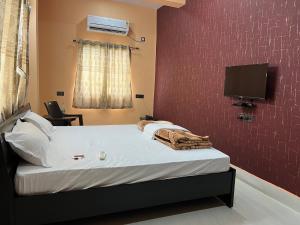 um quarto com uma cama e uma televisão na parede em Hotel Krishna Paradise em Deoghar