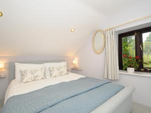 a white bedroom with a bed and a window at Lydgate House Cottage in Yelverton