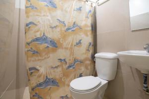 a bathroom with a shower curtain with a toilet and a sink at Shorebreak Boracay Resort in Boracay