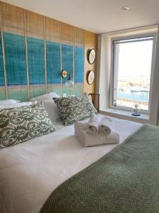 een slaapkamer met 2 handdoeken op een bed met een raam bij La Maison du Vieux Port in Flamanville