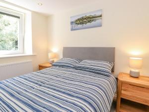 a bedroom with a bed with a blue and white striped comforter at Ladstock Cottage in Keswick