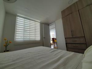 - une chambre avec un lit blanc et une fenêtre dans l'établissement Apartamento en conjunto hacienda Peñaliza Limonar, à Ricaurte