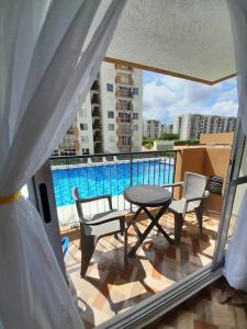 d'un balcon avec une table, des chaises et une piscine. dans l'établissement Apartamento en conjunto hacienda Peñaliza Limonar, à Ricaurte