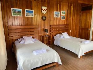 two beds in a room with wood paneled walls at HAUS KÖHEL HOSPEDAJE POZUZO in Pozuzo