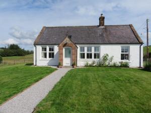 una pequeña casa blanca con un patio de césped en Marr Cottage, en Thornhill