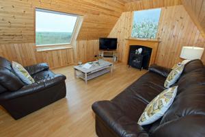 a living room with two leather couches and a fireplace at Canach Cottage in Pollachar