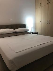 um quarto com uma grande cama branca e um candeeiro em Porto Rafti Holiday Apartment em Porto Rafti
